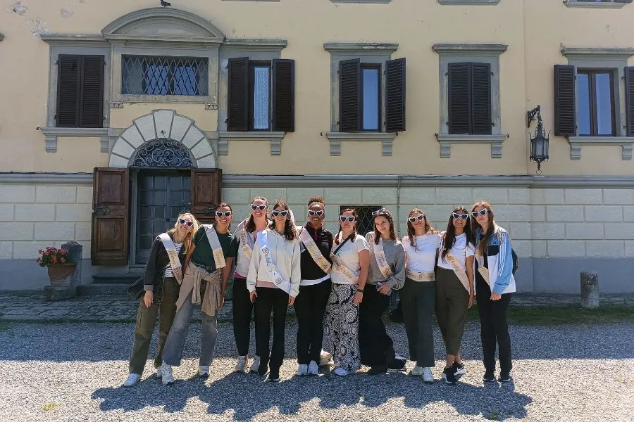 Gruppo di amiche durante un weekend di addio al nubilato nel Chianti davanti a una villa toscana.
