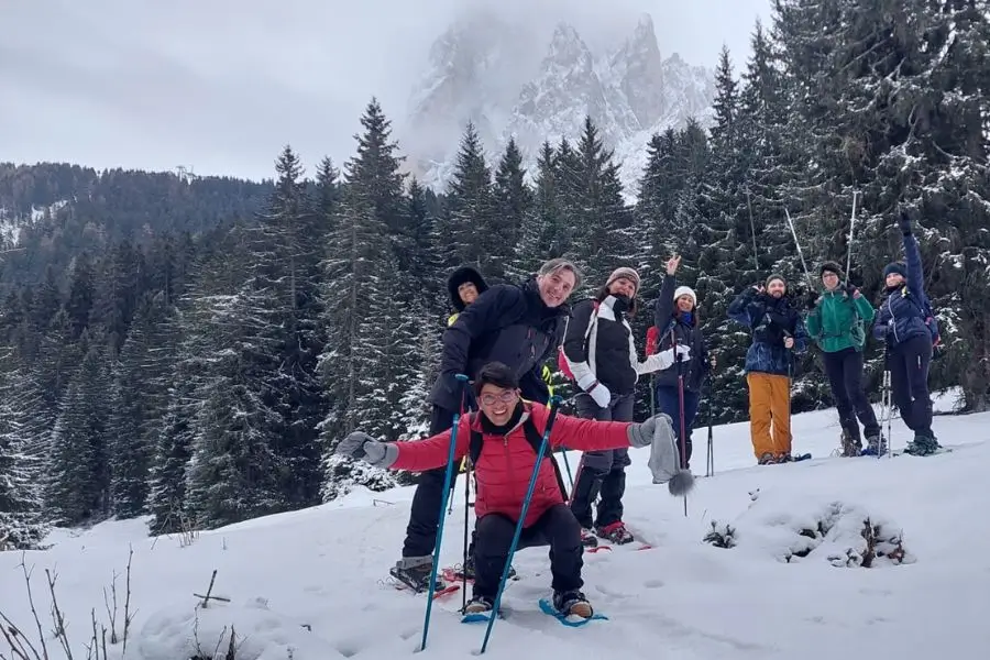 A group of smiling WeHike hikers during a snowshoe hike in the snowy Dolomites.
