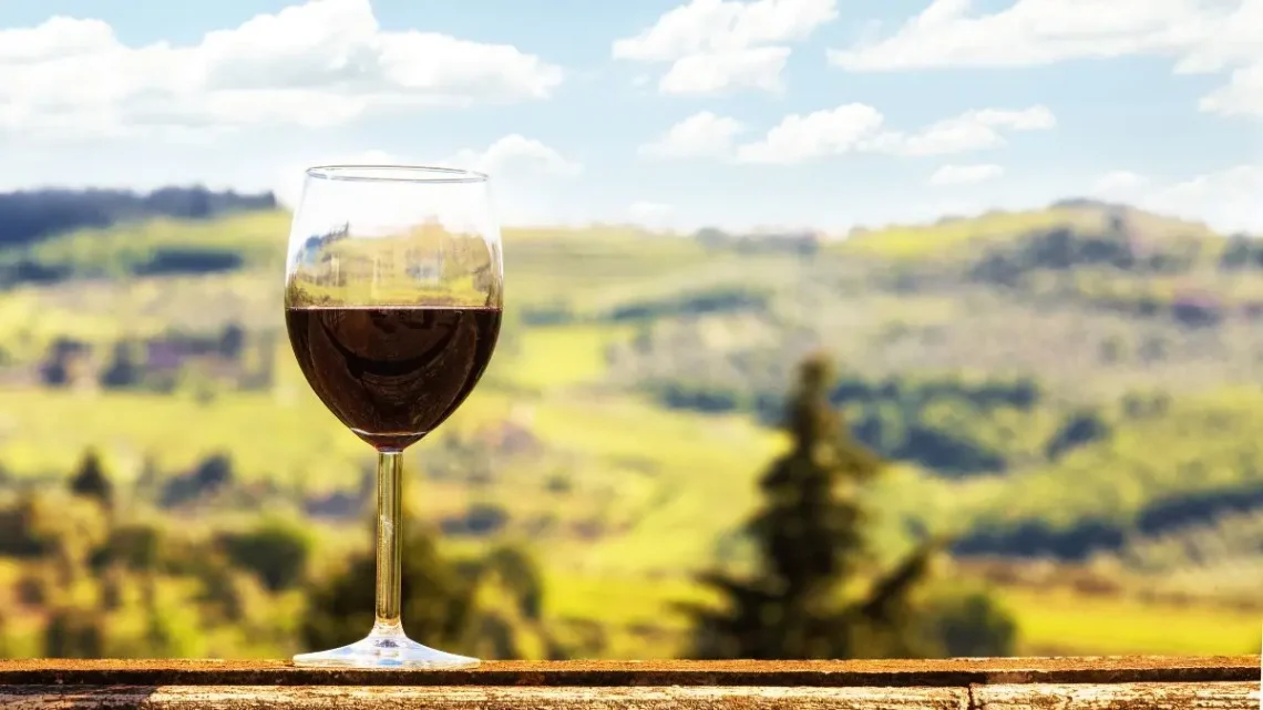 Calice di vino rosso con vista panoramica sulle colline del Chianti